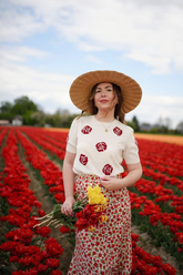 a lady in a white jacquard knit top and a red floral printed skirt